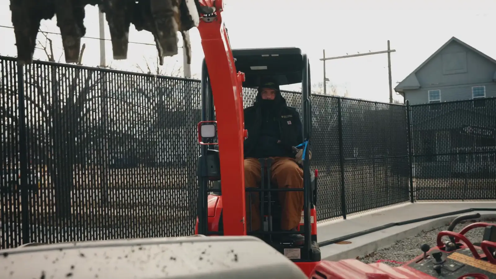 Mini excavator working inside a fenced job site